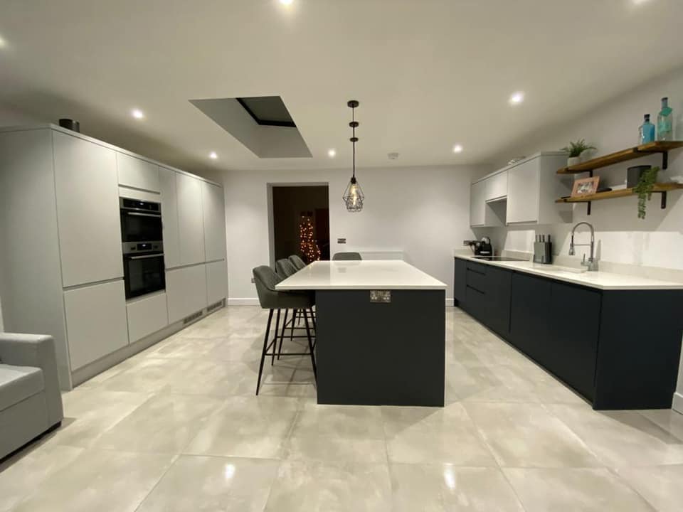 Modern kitchen with white cabinetry, black island, and polished marble flooring