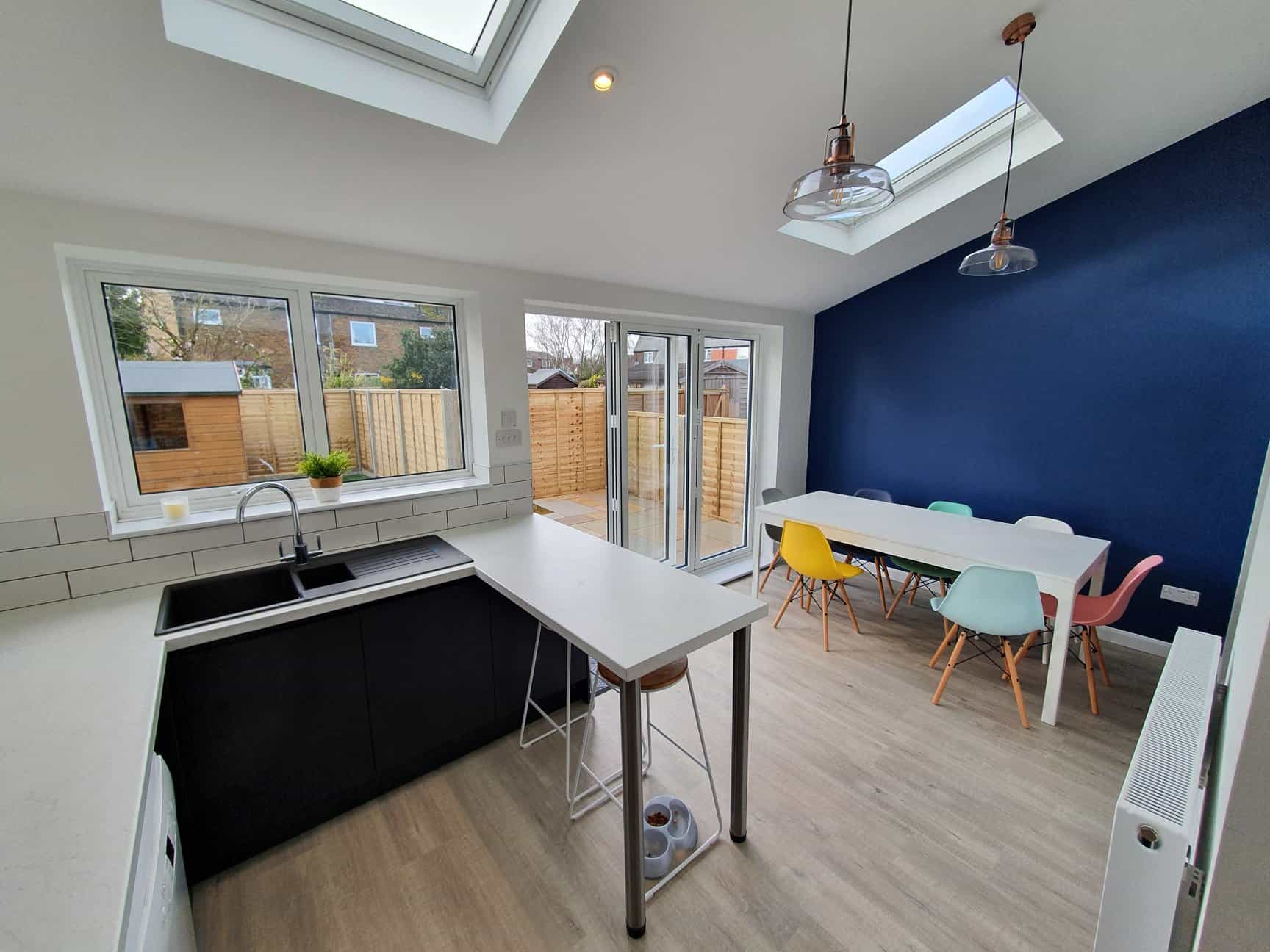 Modern kitchen extension with skylights, black sink, and blue accent wall