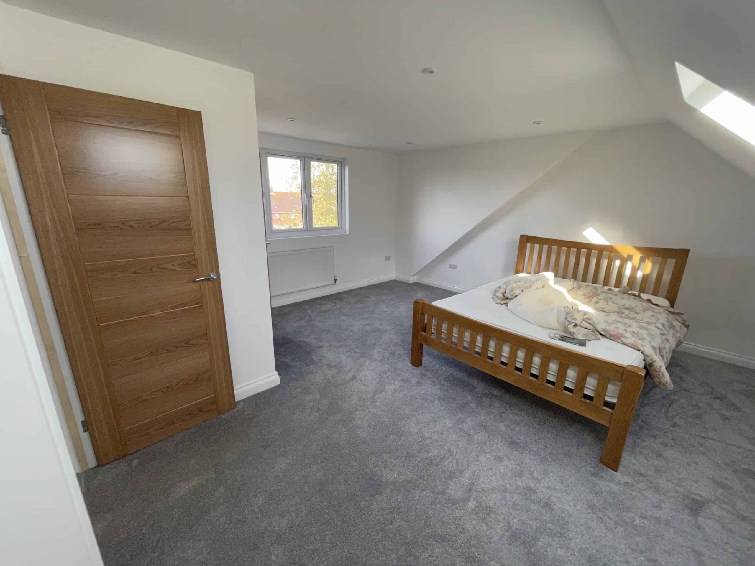 Modern bedroom with wooden bed and oak door in new construction
