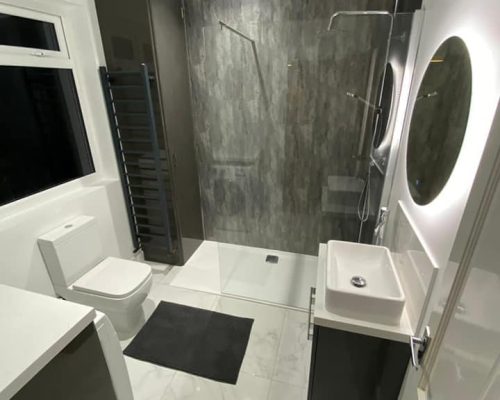 Modern bathroom with walk-in shower, grey tile, and white fixtures